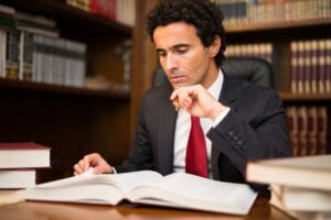 Man in suit reading large legal book