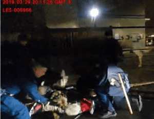 Officers restraining person on ground at night