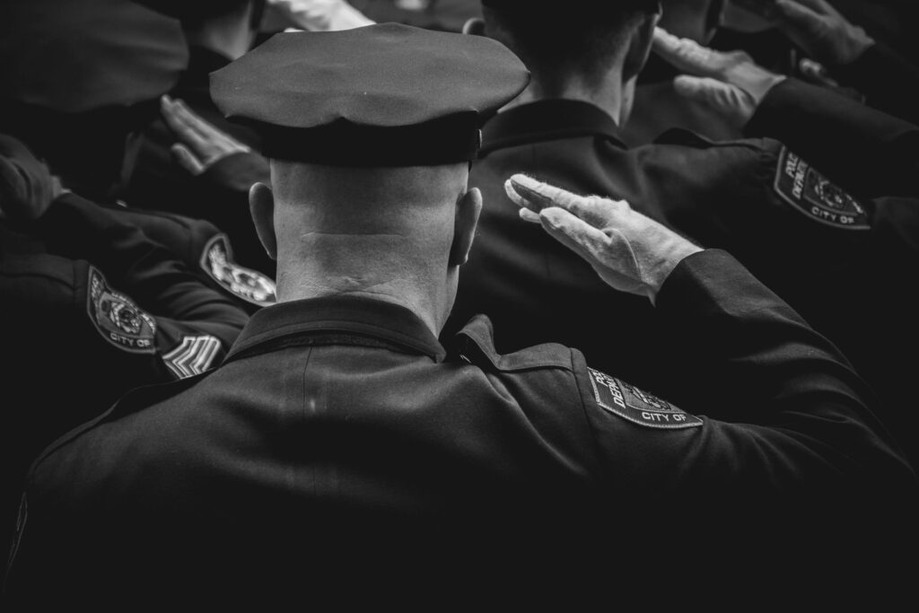 Black and white officers saluting at ceremony
