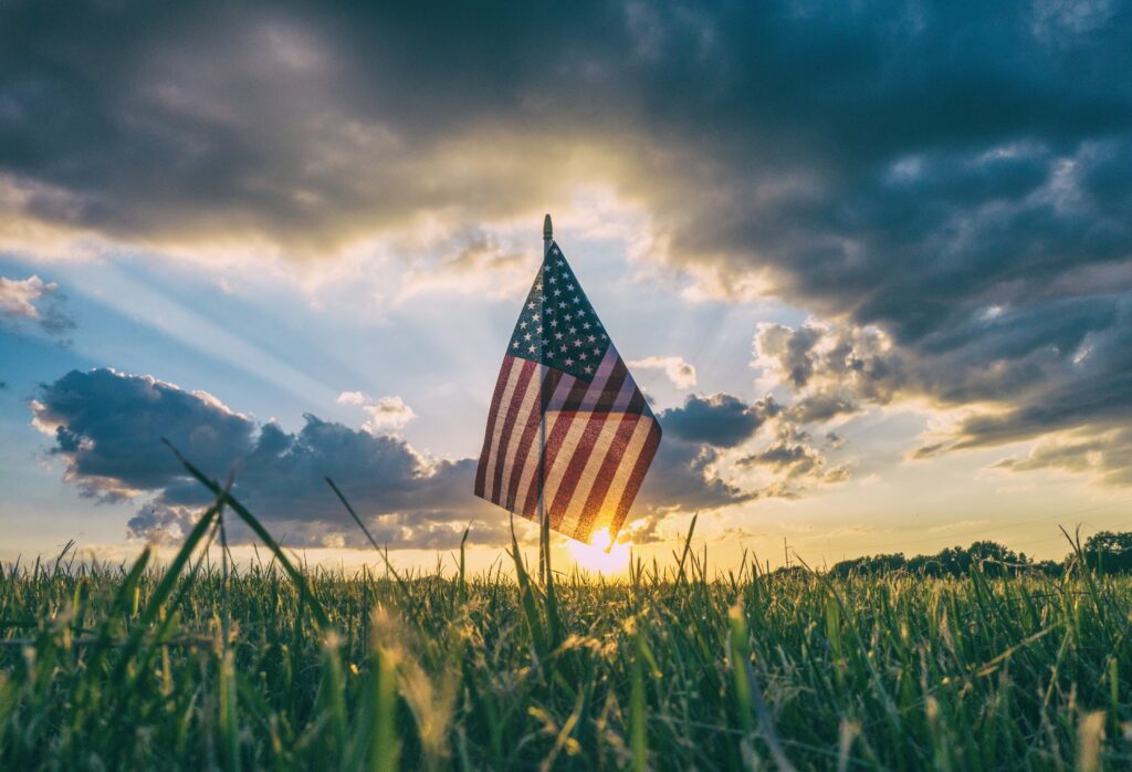American flag silhouetted against sunset sky