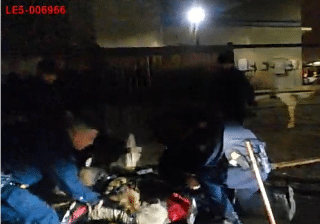Officers restraining person on ground at night