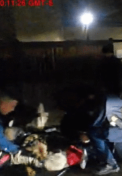 Officers restraining person on ground at night