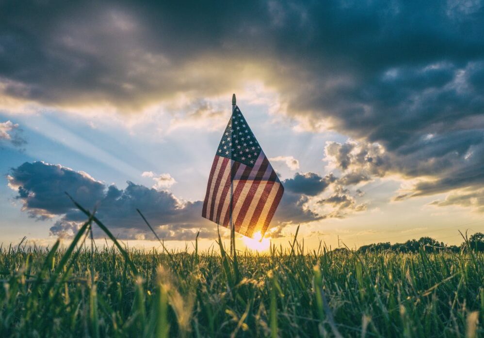 American flag silhouetted against sunset sky