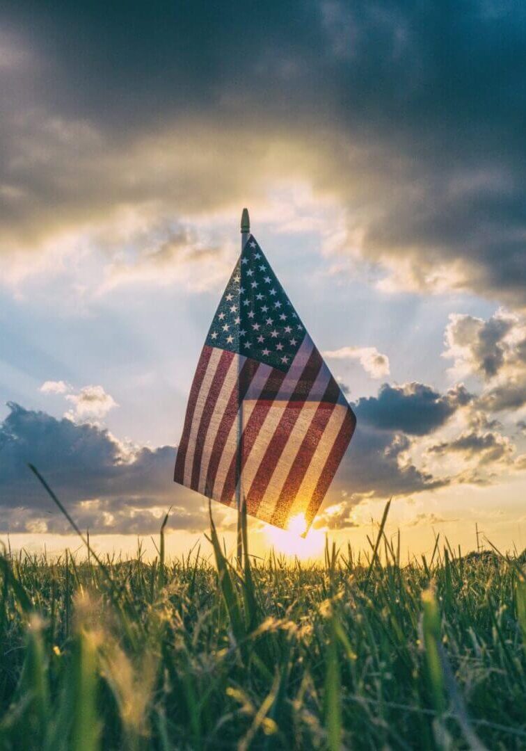 American flag silhouetted against sunset sky