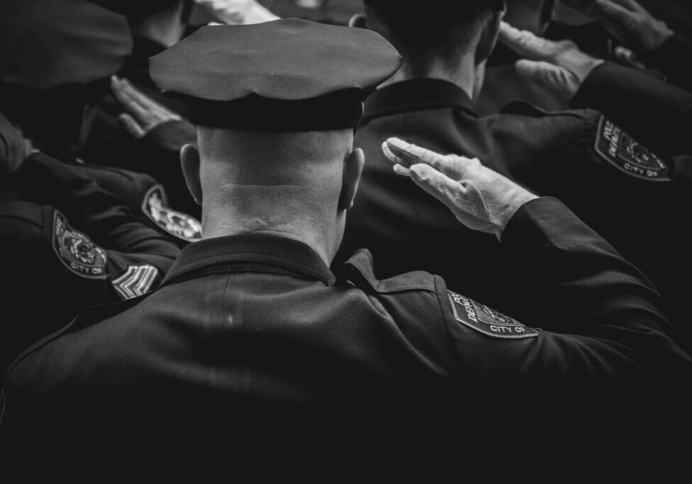 Black and white officers saluting at ceremony