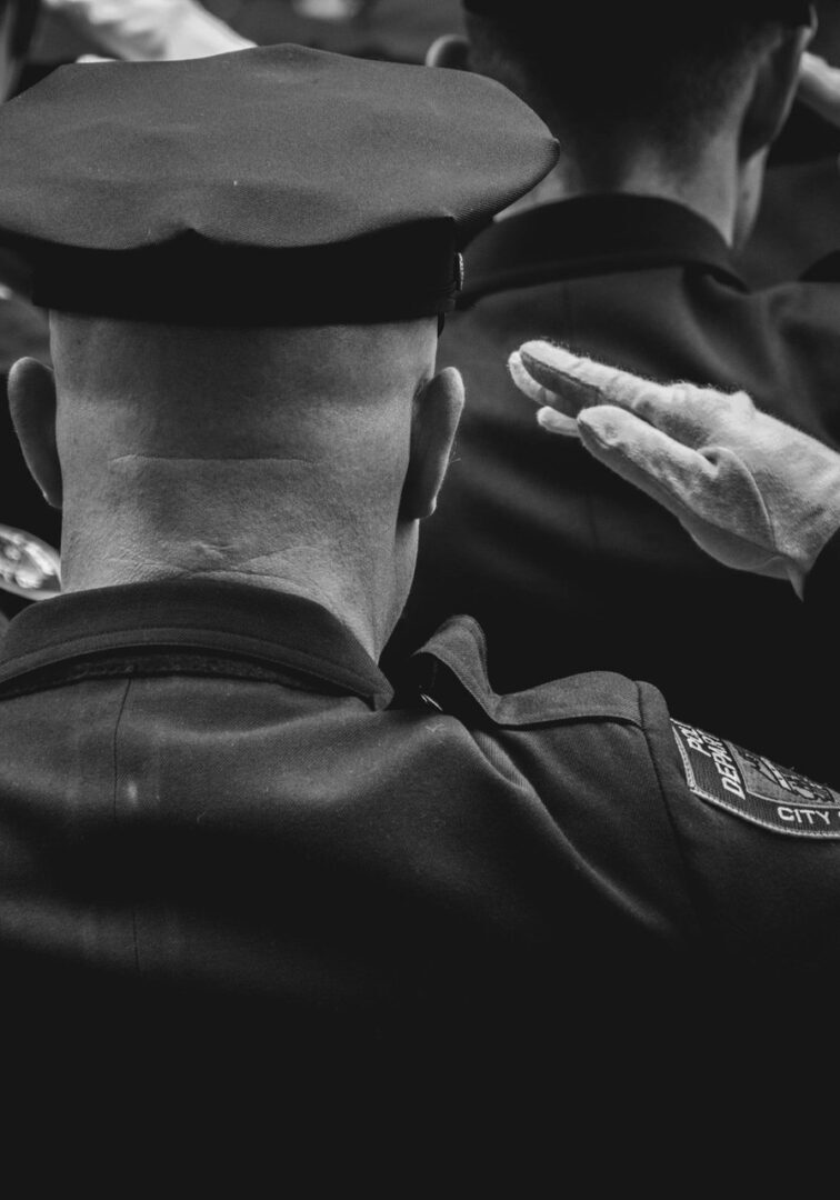 Black and white officers saluting at ceremony