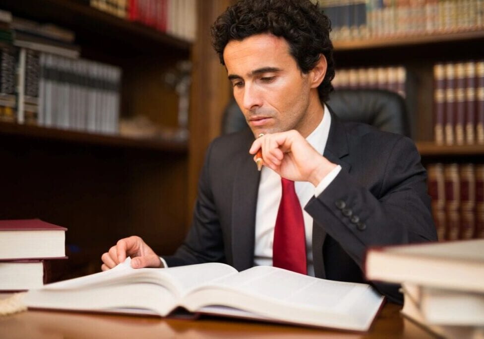 Man in suit reading large legal book